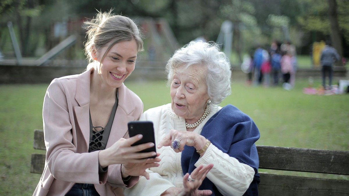 Woman holds phone and shows senior citizen