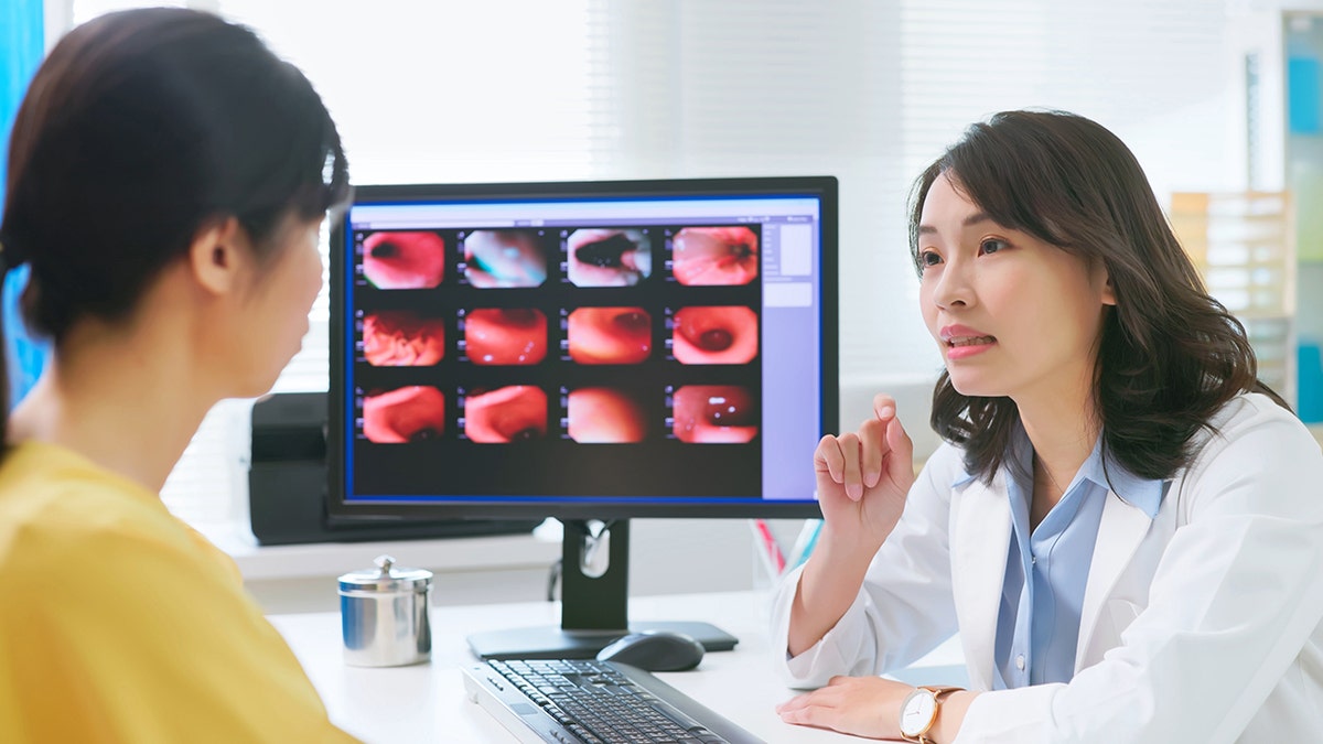 Doctor discussing endoscopy results with a patient while reviewing gastrointestinal images on a computer screen.