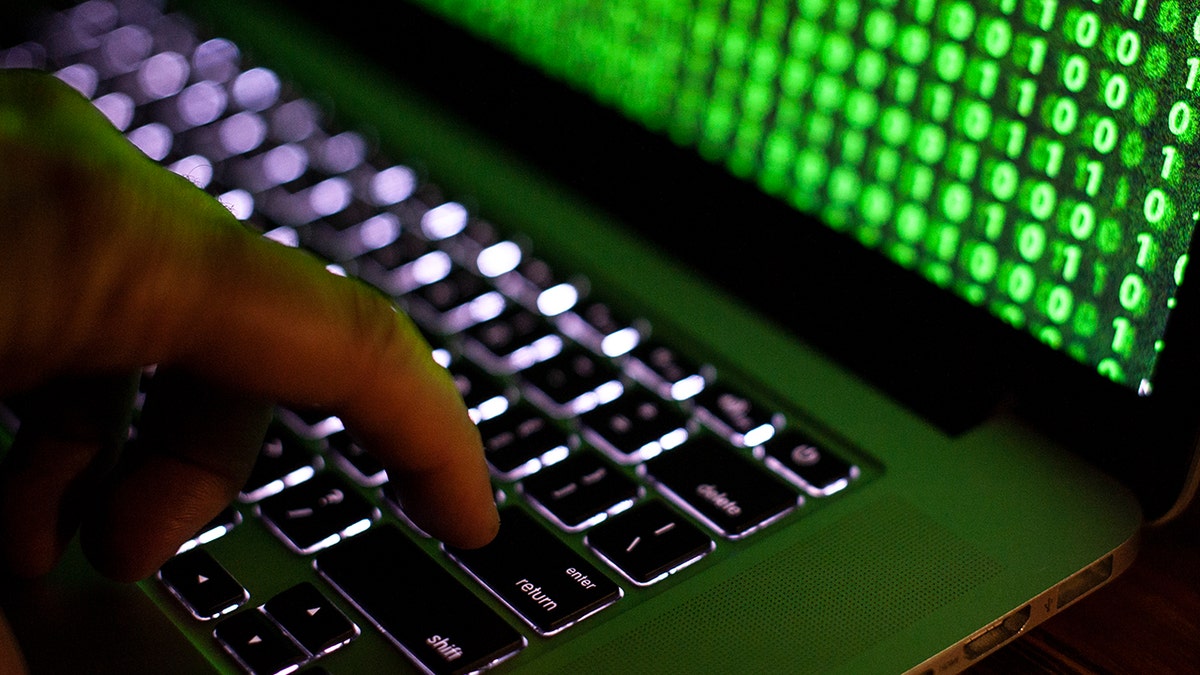 Hacker typing code on his laptop.