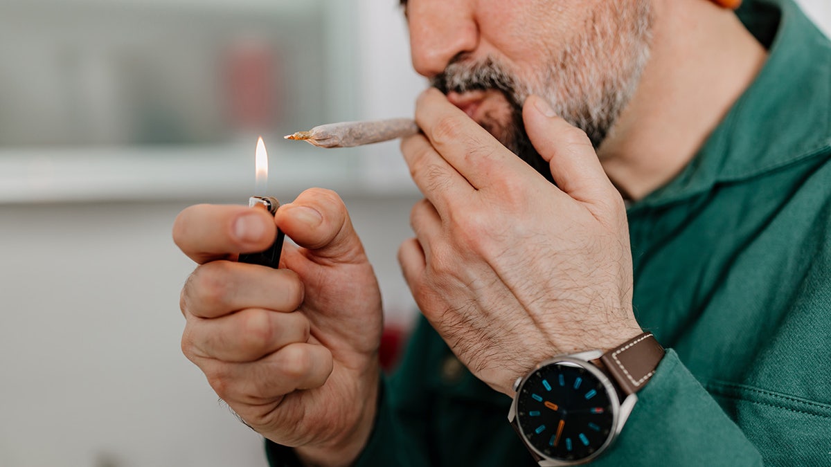man taking a hit of marijuana joint