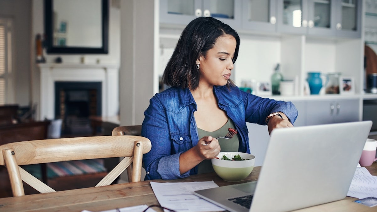 Woman checking watch while eating
