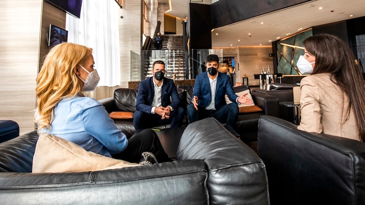 Masked people talking in hotel lobby - flu spread