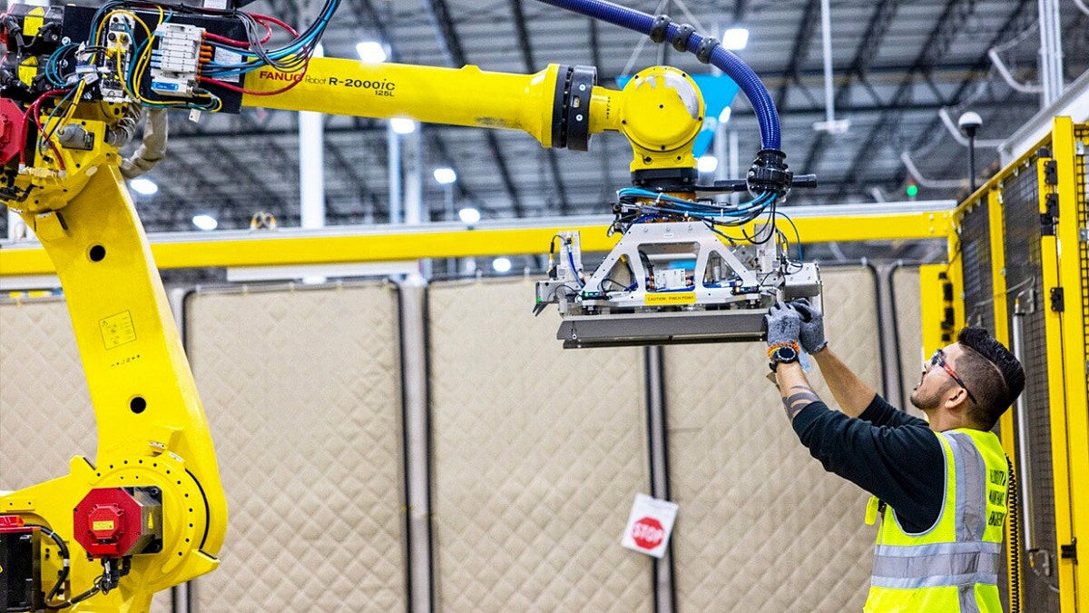 A warehouse worker inspecting the Blue Jay robot