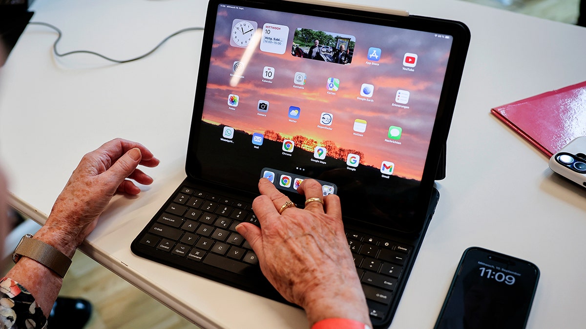 An elderly person uses an Apple iPad.
