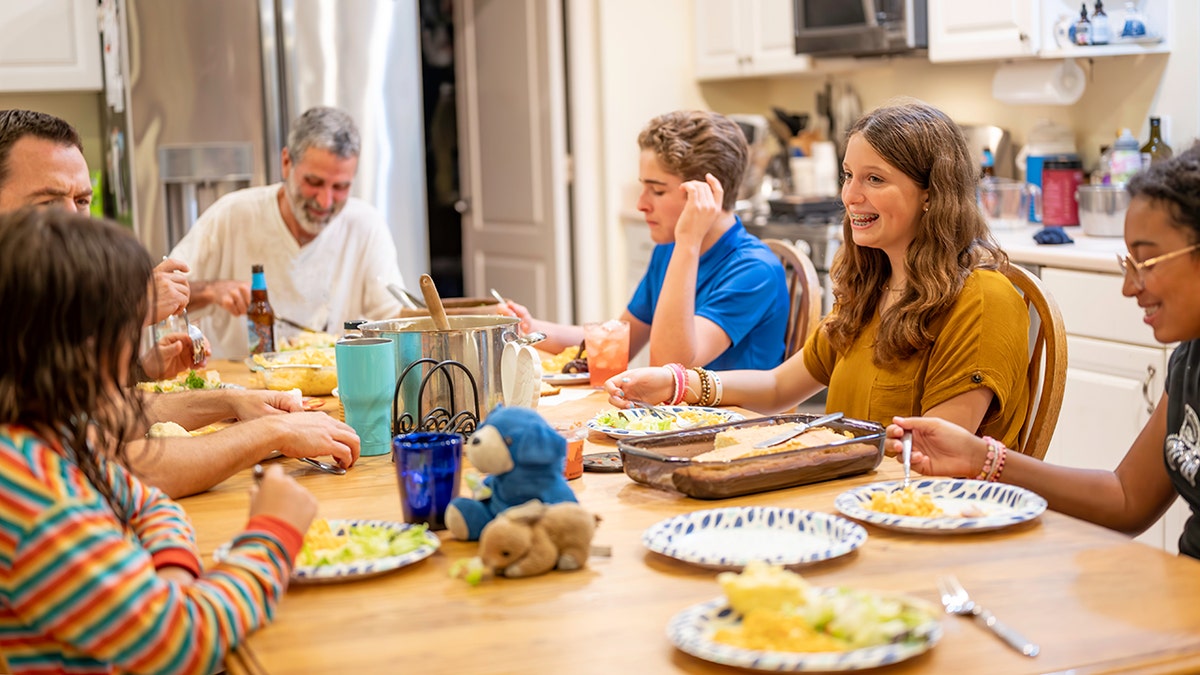 Large family gathered around a kitchen table sharing a home-cooked dinner together.