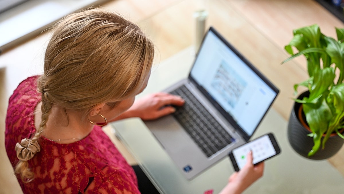 Woman typing on her laptop and phone.
