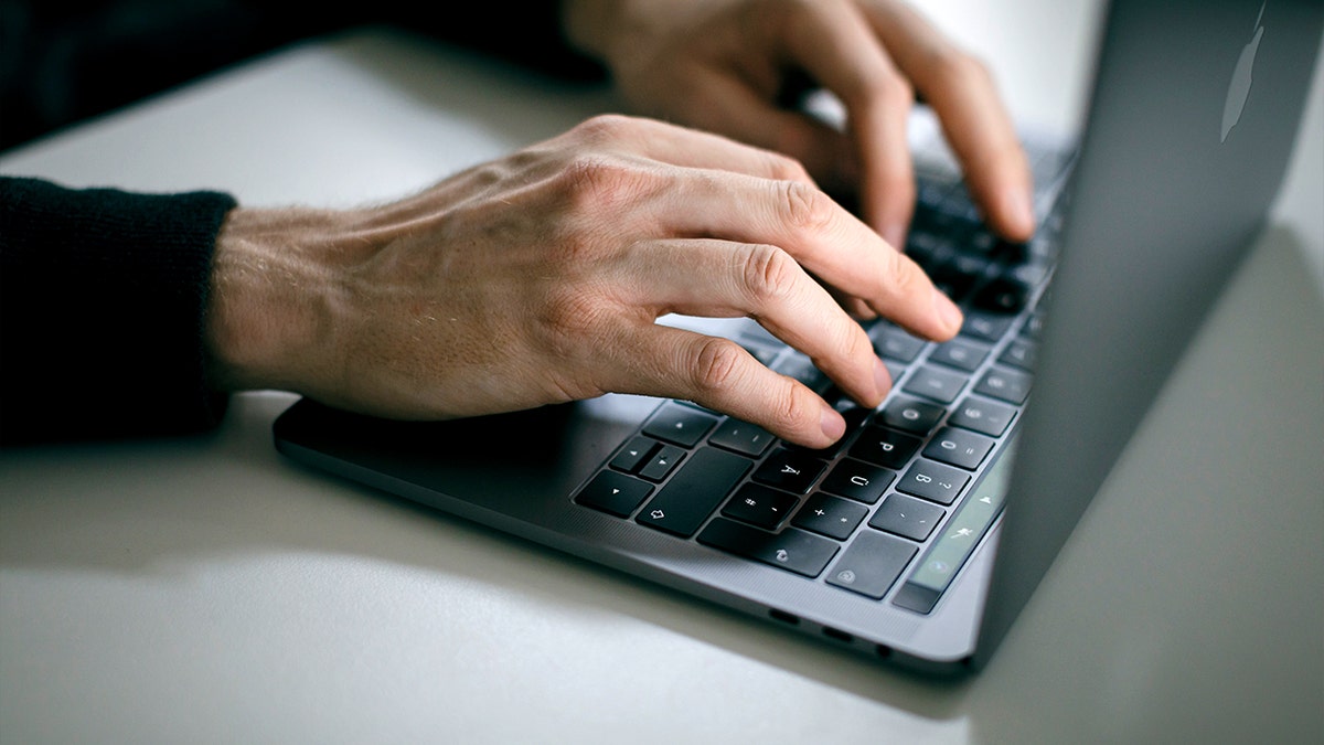 A person types on a laptop keyboard.
