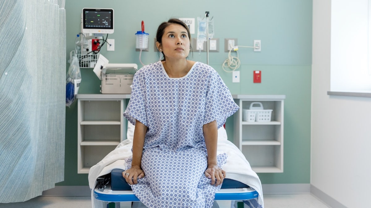 Woman sitting on hospital bed looking concerned