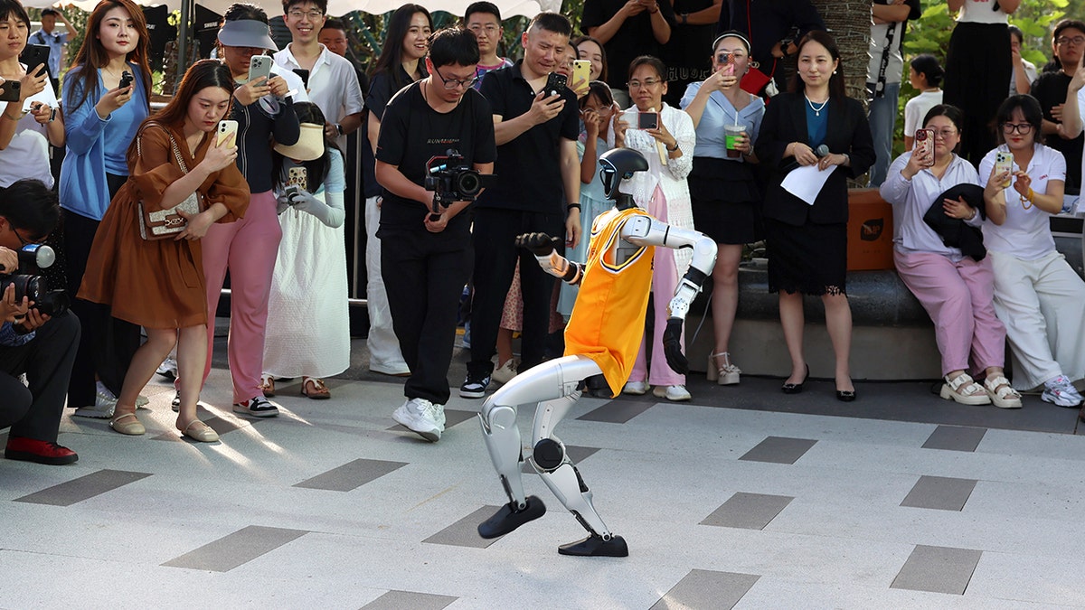 A robot dances as a crowd looks on.