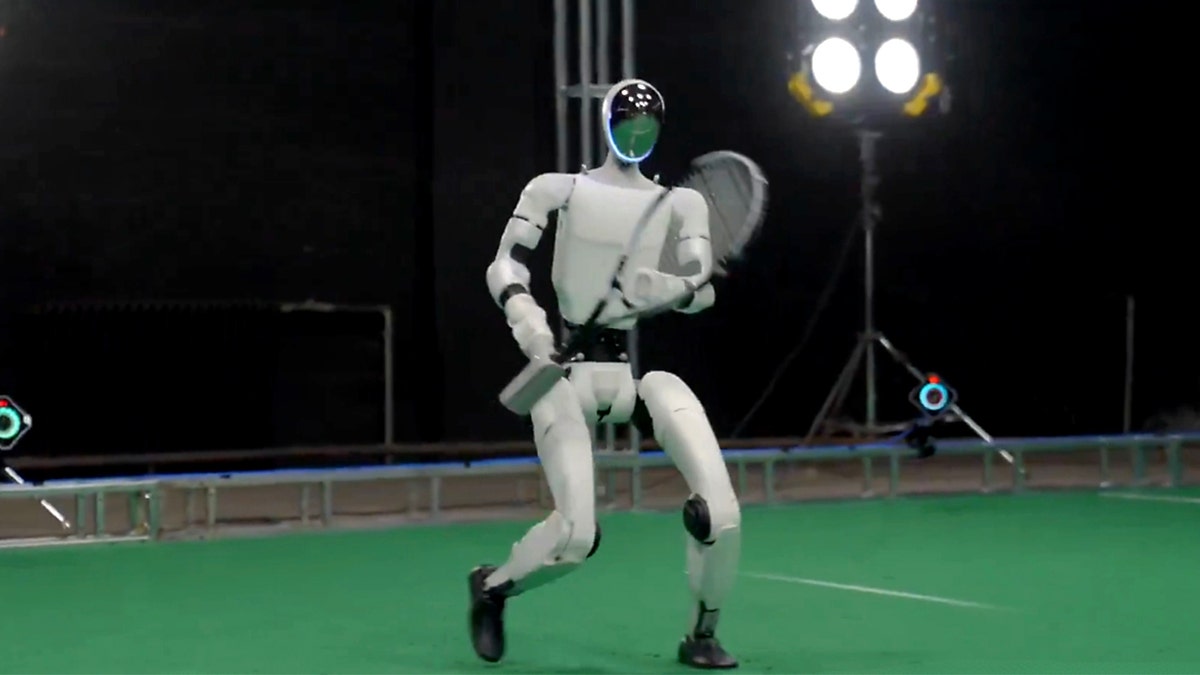 A humanoid robot holds a tennis racket.