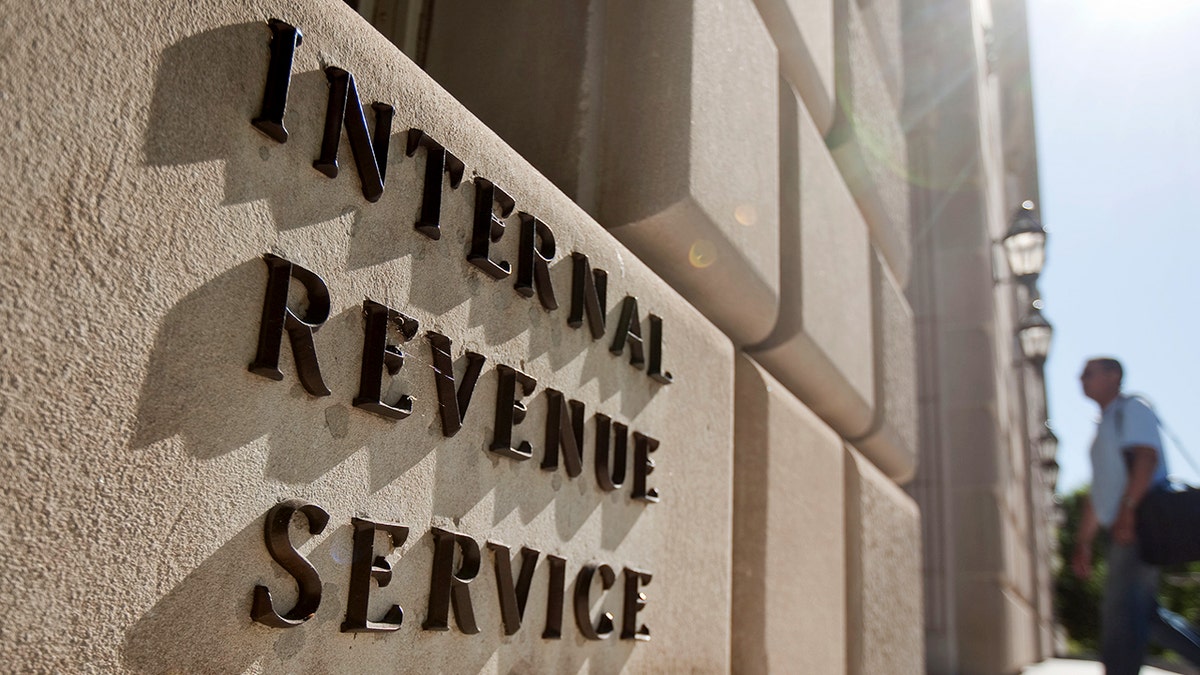 A man walks into a building with lettering on the facade reading "Internal Revenue Service."