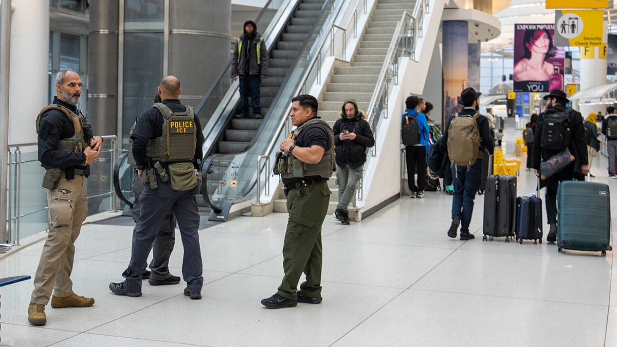 ICE agents walking through a terminal at JFK Airport.