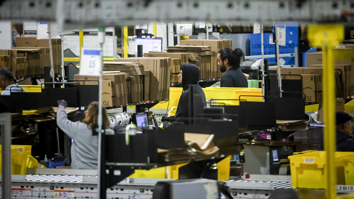 Workers stand on an assembly line in an Amazon warehouse.