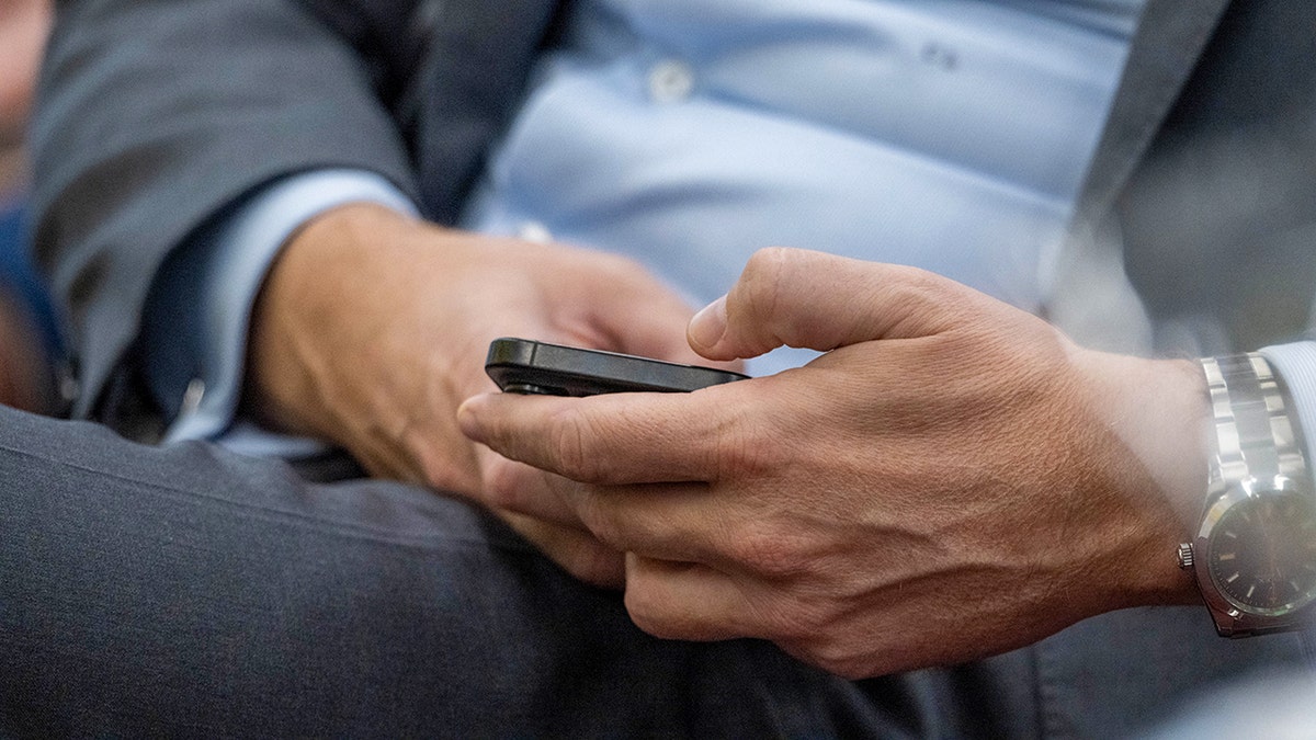 Man in a suit typing on his phone