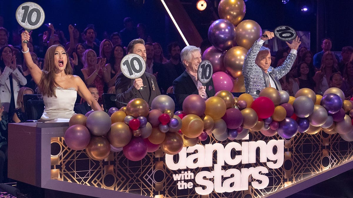 Tom Bergeron with Carrie Ann Inaba, Derek Hough, and Bruno Tonioli on Dancing with the Stars set