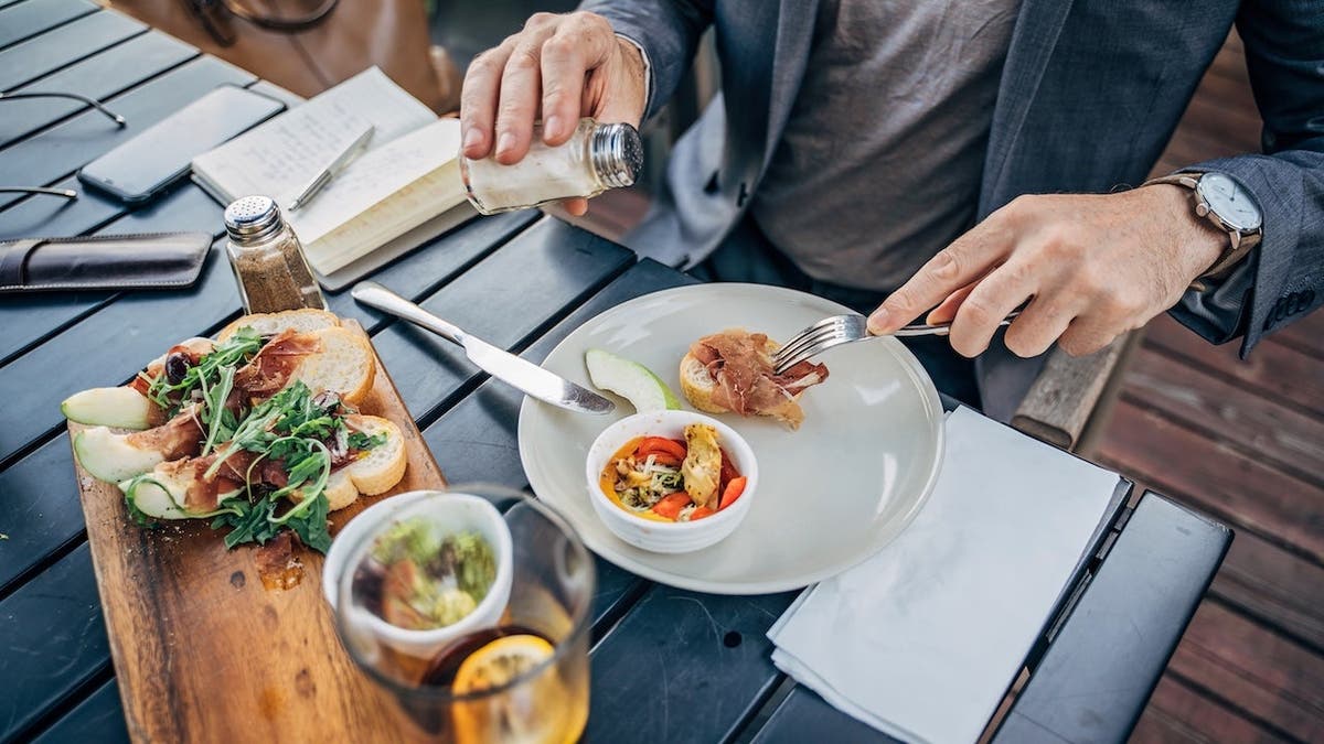 Handsome mature man eating lunch alone at outdoor restaurant.