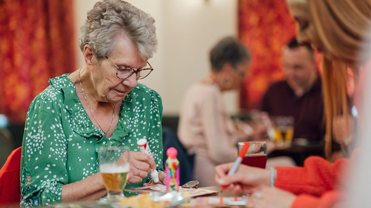 Senior woman and granddaughter playing bingo together at a social club