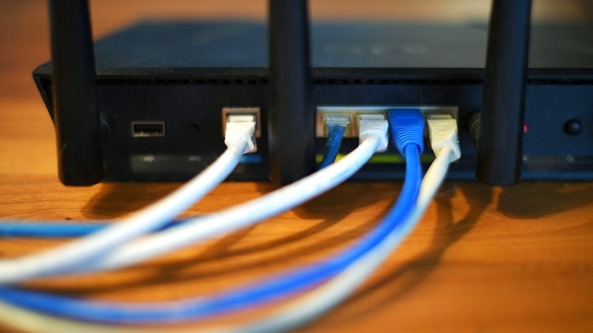 Wires plug into the back of a Wi-Fi router.