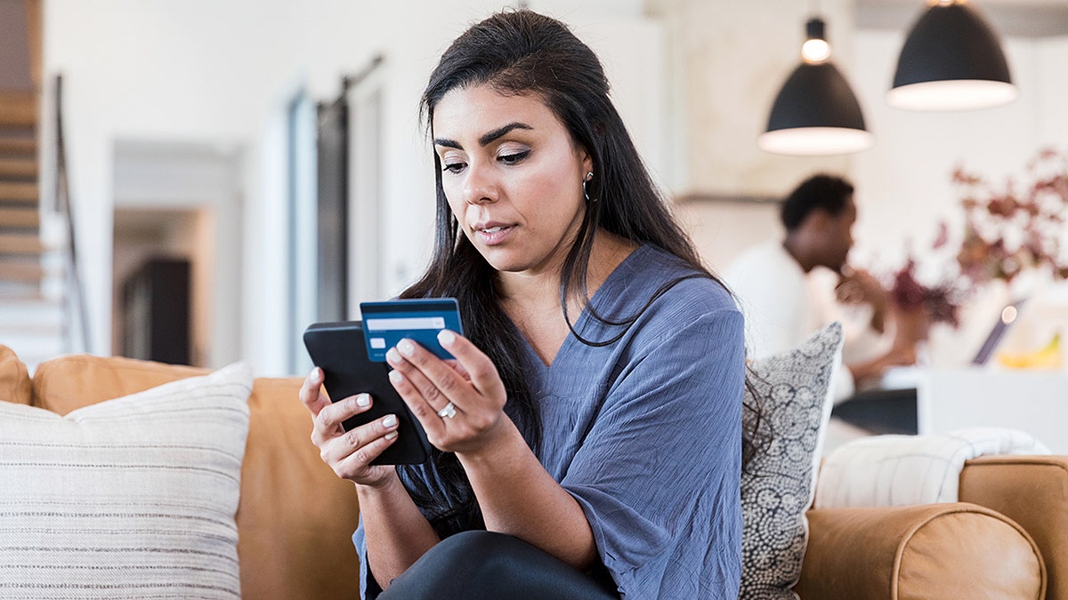 Serious woman entering credit card information on phone while shopping online